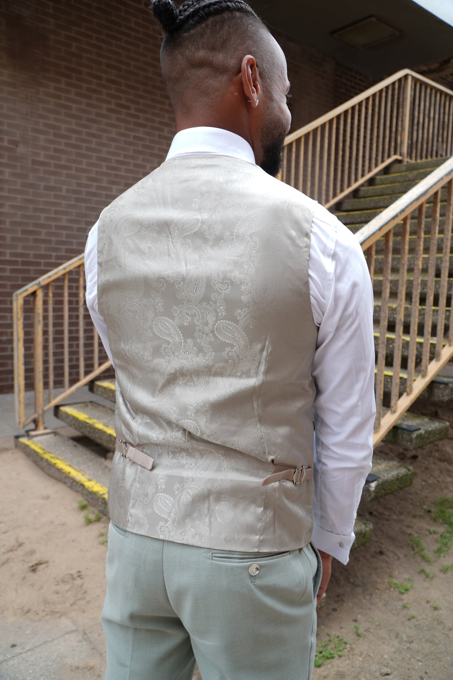 Back view of the SUITBAE Callum Sage Three-Piece Suit — featuring a paisley silk waistcoat back with adjustable strap and light sage green trousers, ideal for weddings, proms and summer occasions.