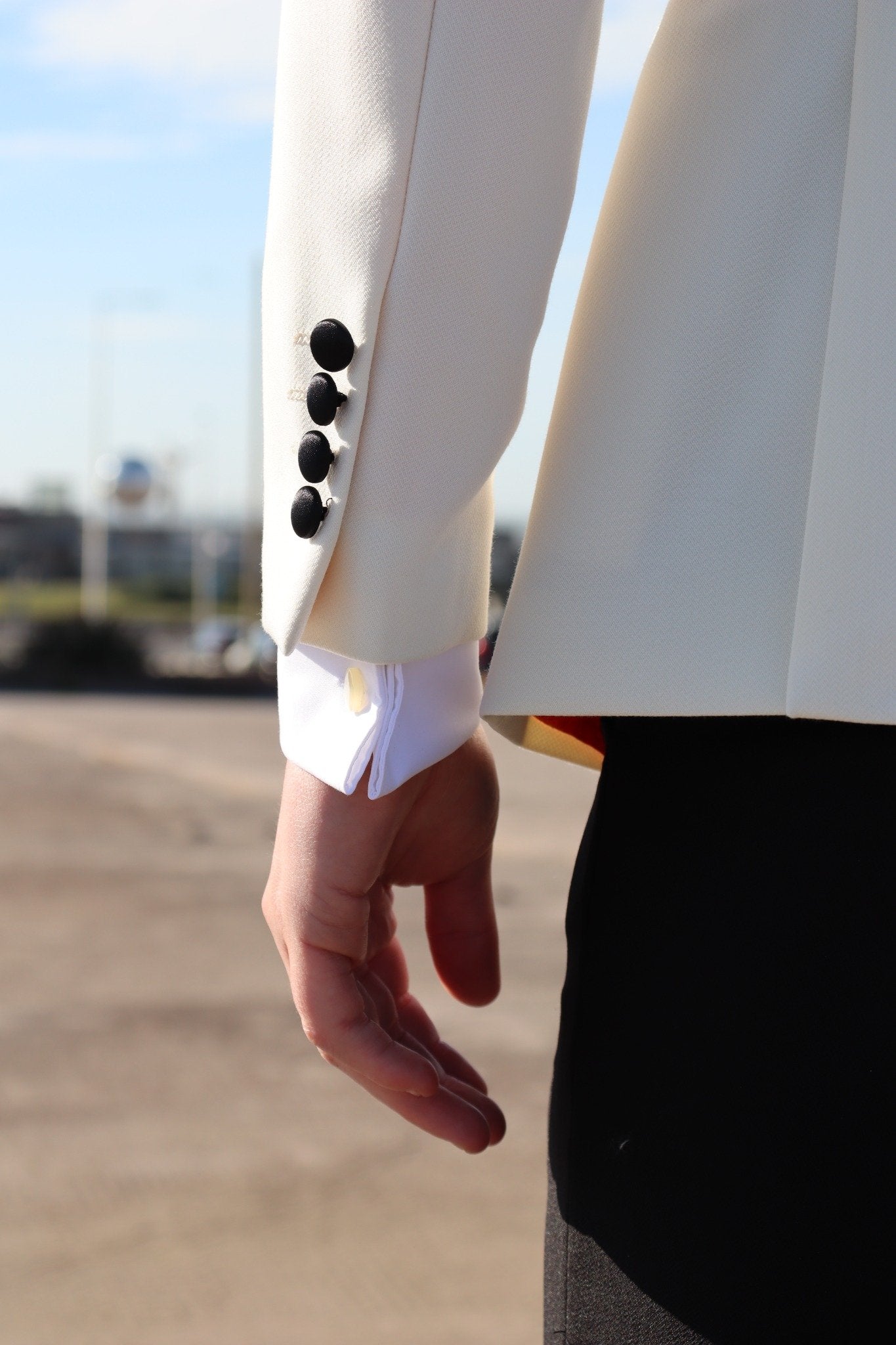 Close-up of the SUITBAE Diablo Ivory Tuxedo sleeve showing black fabric-covered buttons, premium ivory fabric and satin trim — luxury formalwear detail ideal for weddings, proms and black-tie events.
