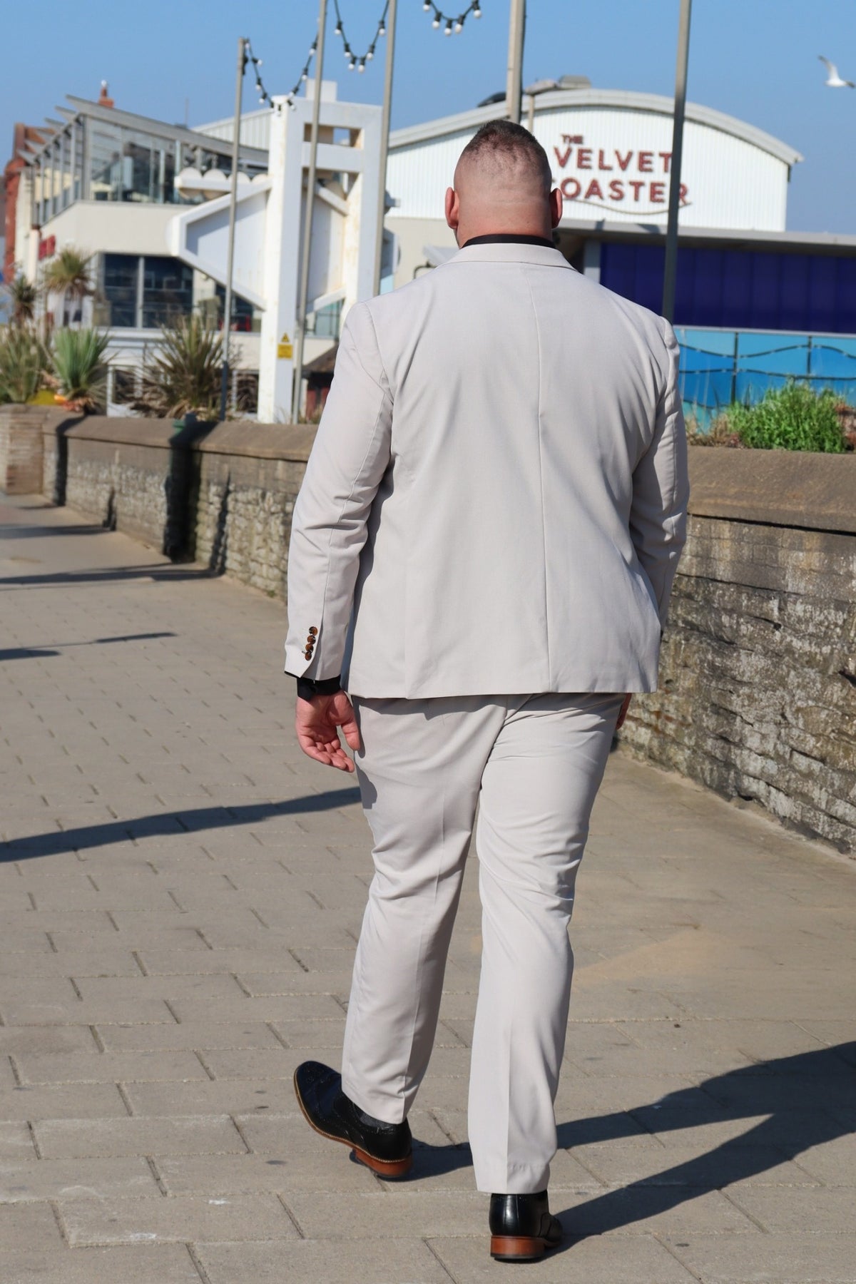 Back view of the SUITBAE Kian Stone Three-Piece Suit — tailored stone beige design with brown button detailing, available in plus sizes, crafted for weddings, proms and summer formal occasions.