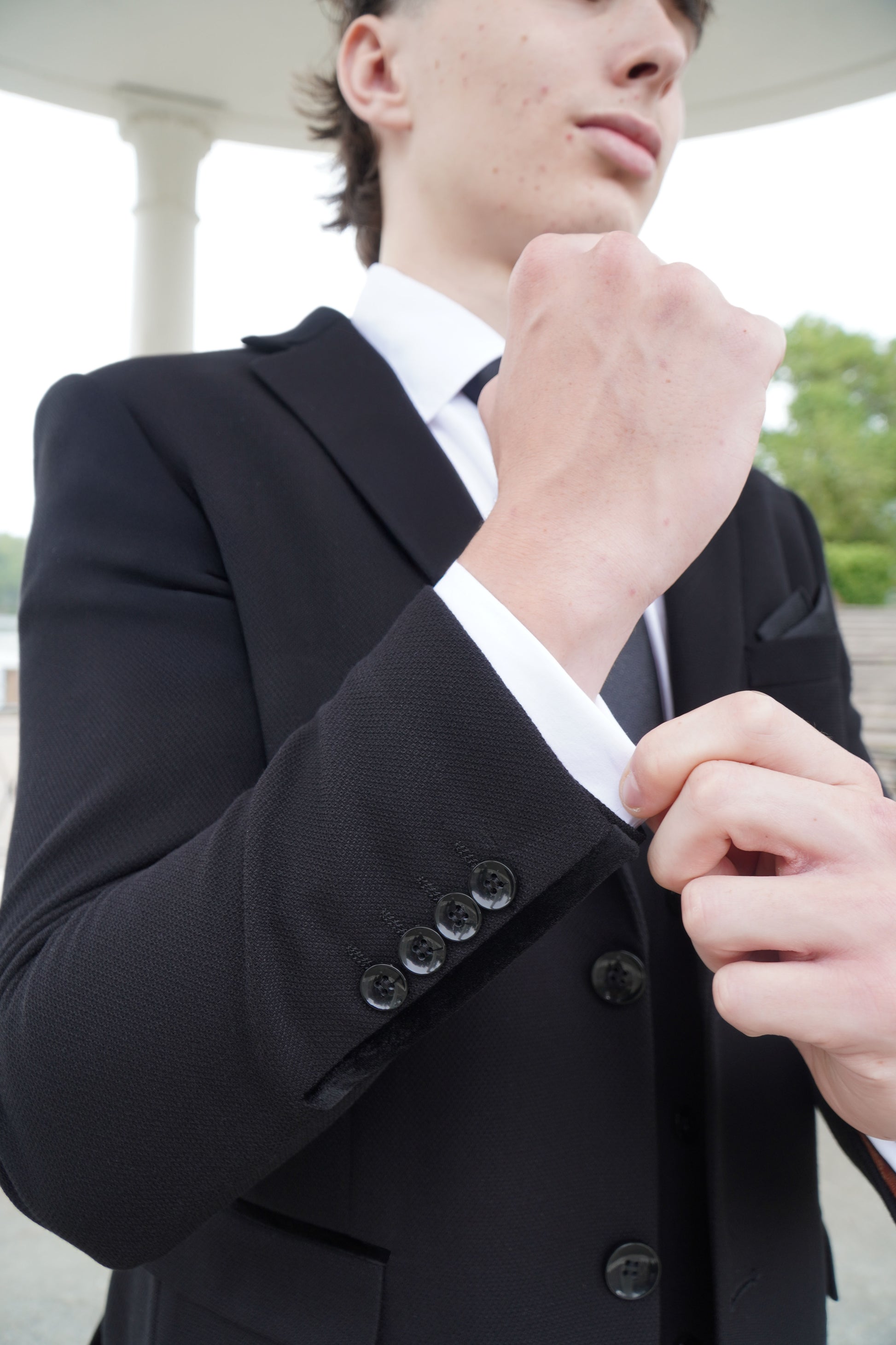 Close-up of the SUITBAE Majid Textured Three-Piece Suit — showcasing the black textured fabric, velvet trim on the sleeve and buttoned cuff detail, crafted for weddings and formal occasions.