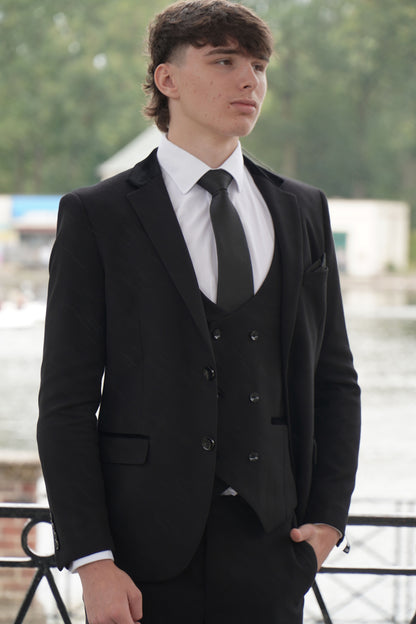Model wearing the SUITBAE Majid Textured Three-Piece Suit — sleek black tailored design with subtle fabric texture, styled with a white shirt and black tie for weddings, proms and formal occasions.