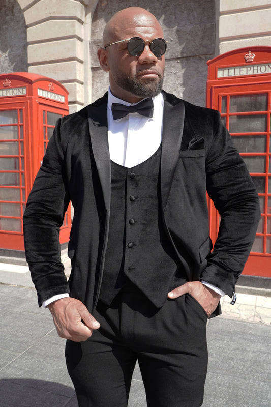Model wearing the SUITBAE Black Velvet Three-Piece Tuxedo — featuring a soft velvet blazer with satin peak lapels, matching waistcoat and trousers, perfect for weddings, galas and black-tie events.