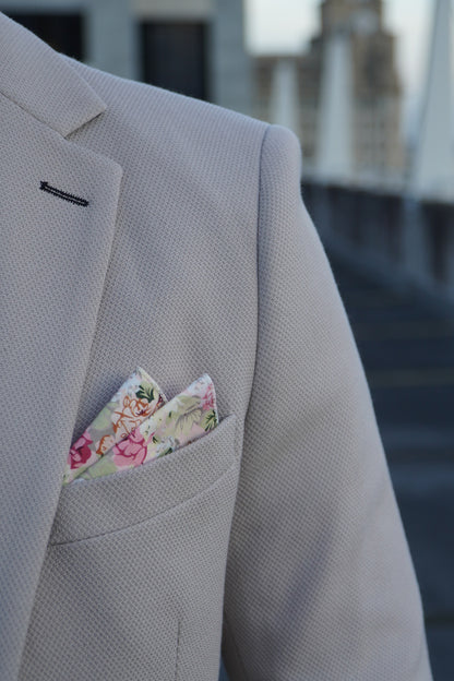 Close-up of the SUITBAE Escobar Stone Three-Piece Suit — beige textured fabric with floral pocket square detail, showcasing refined tailoring ideal for weddings and summer events.