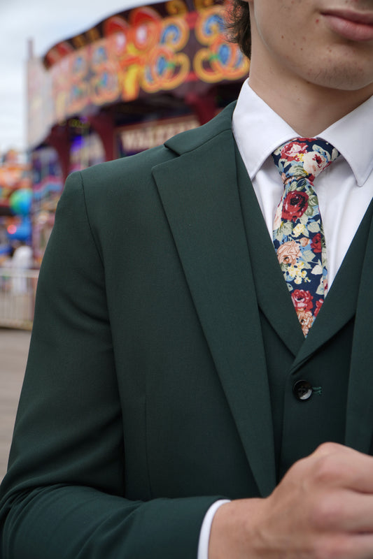 Close-up of the SUITBAE Archie Green Three-Piece Suit — rich green textured fabric with notch lapels, styled with a floral tie for weddings, proms and race day occasions.