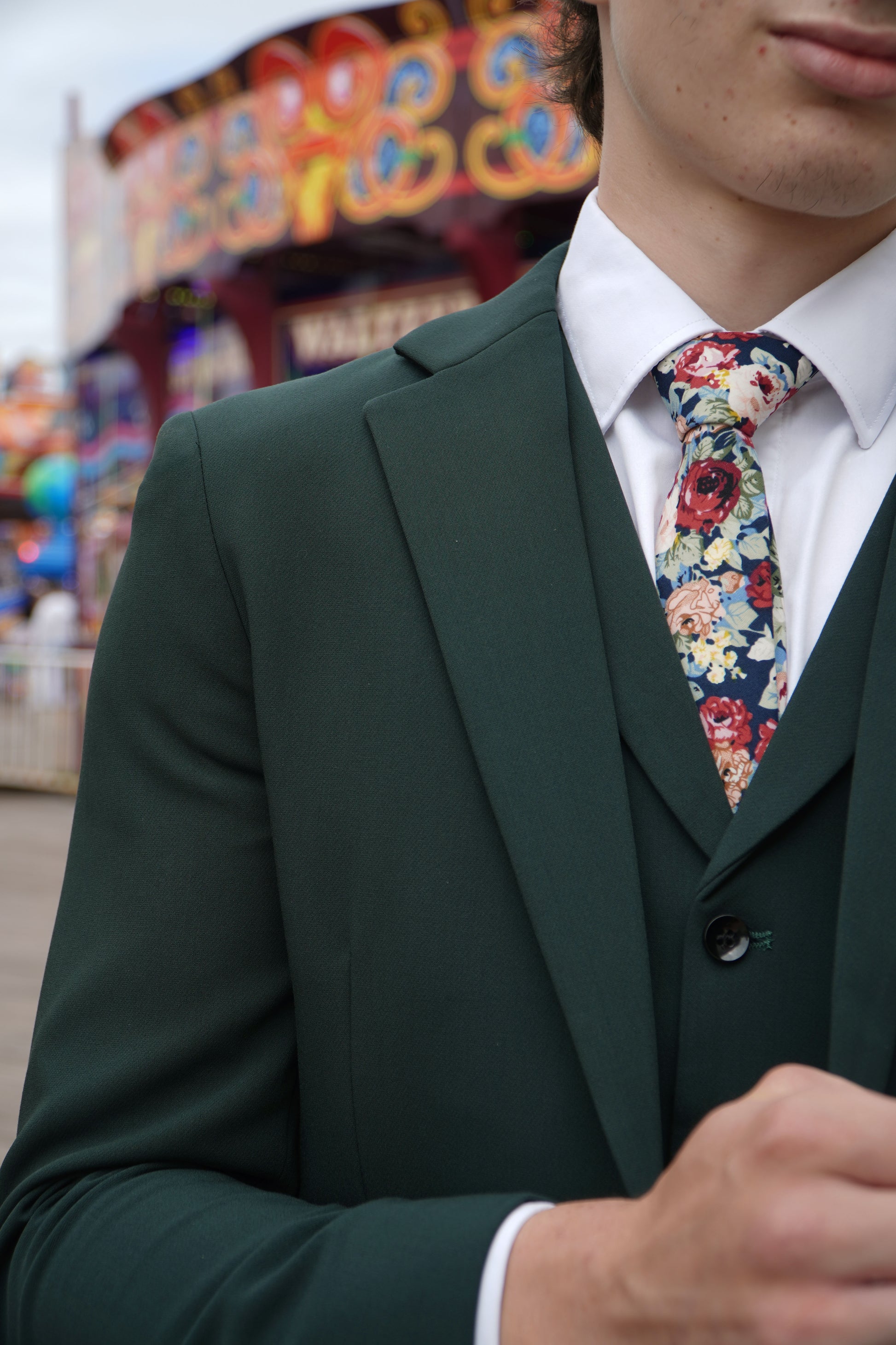 Close-up of the SUITBAE Archie Green Three-Piece Suit — showcasing the rich green textured fabric with notch lapels, styled with a floral tie for weddings, proms and race day occasions.