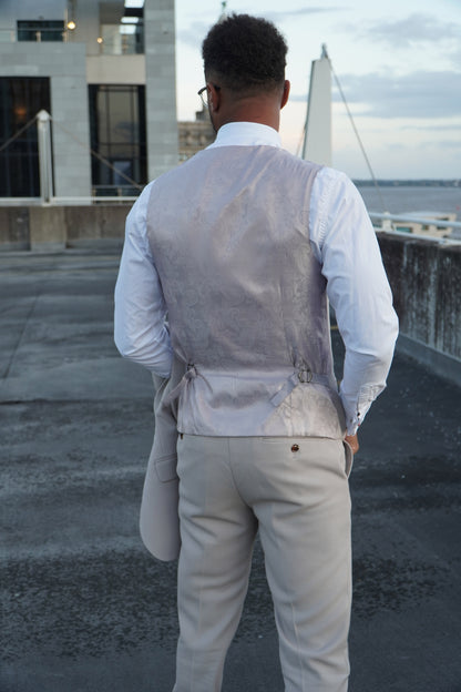 Back view of the SUITBAE Escobar Stone Three-Piece Suit — showing the paisley silk waistcoat back with adjustable strap and tailored beige trousers, perfect for weddings and summer events.