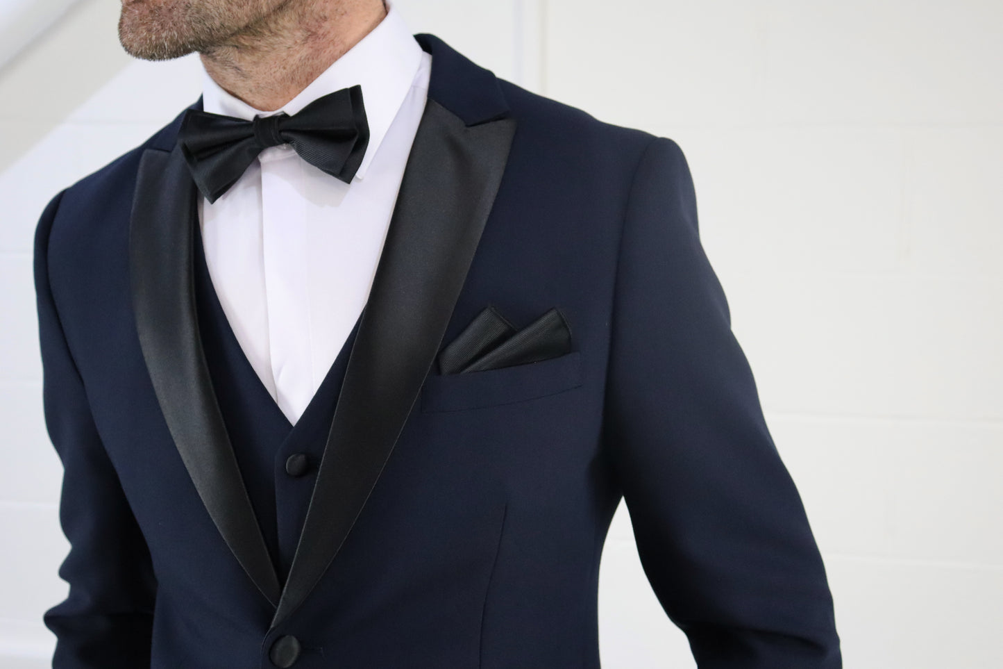 Close-up of the SUITBAE Diablo Navy Tuxedo jacket featuring satin peak lapels and matching pocket square — a refined navy tuxedo for weddings, galas, and black-tie events.