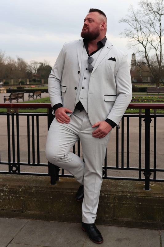Model wearing the SUITBAE Charles Stone Three-Piece Suit with a black shirt and matching pocket square. The stone fabric with a subtle pattern and black contrast trim creates a bold, refined style. Available in plus sizes, ideal for weddings, races, and formal occasions.