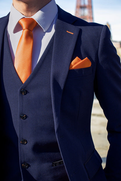 Close-up of the SUITBAE Charles Navy Three-Piece Suit showing the textured navy fabric, notch lapel, and matching waistcoat. Styled with a bold orange tie and pocket square — SUITBAE’s signature tangerine touch — perfect for weddings, races, and formal occasions. Available in plus sizes.