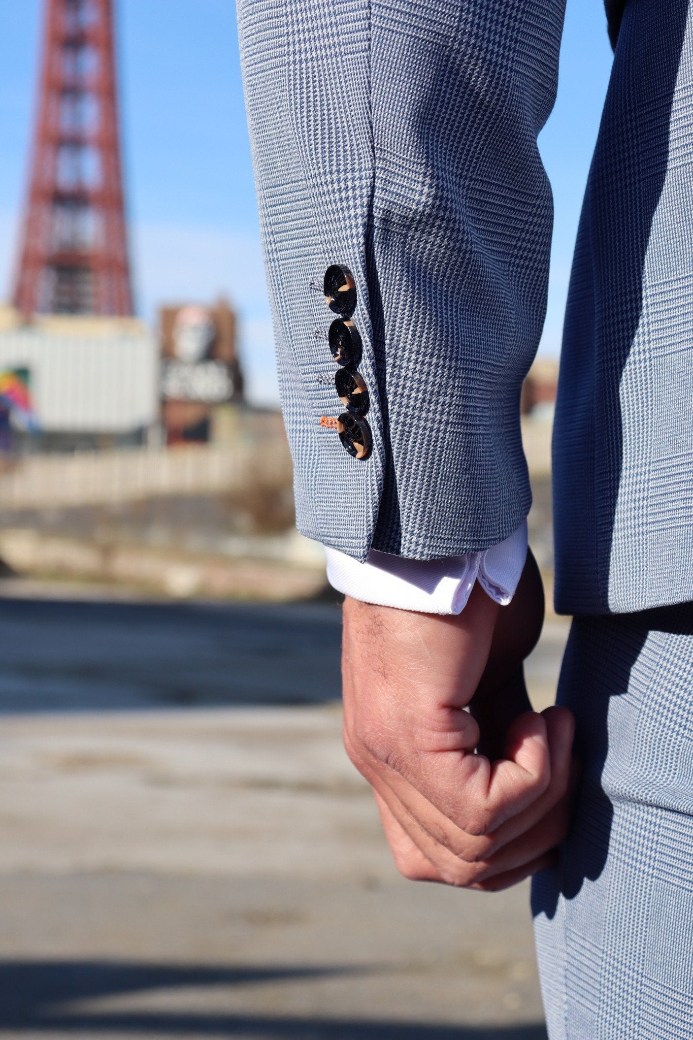 Close-up of the SUITBAE Charles Sky Three-Piece Suit sleeve showing tortoiseshell buttons and fine light blue check fabric, captured on Blackpool Promenade — premium men’s suit for weddings, races and formal occasions, available in plus sizes.