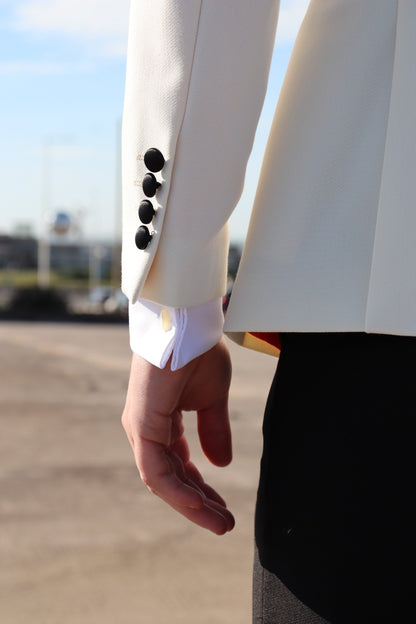 Close-up of the SUITBAE Diablo Ivory Tuxedo sleeve showing black fabric-covered buttons, premium ivory fabric and satin trim — luxury formalwear detail ideal for weddings, proms and black-tie events.