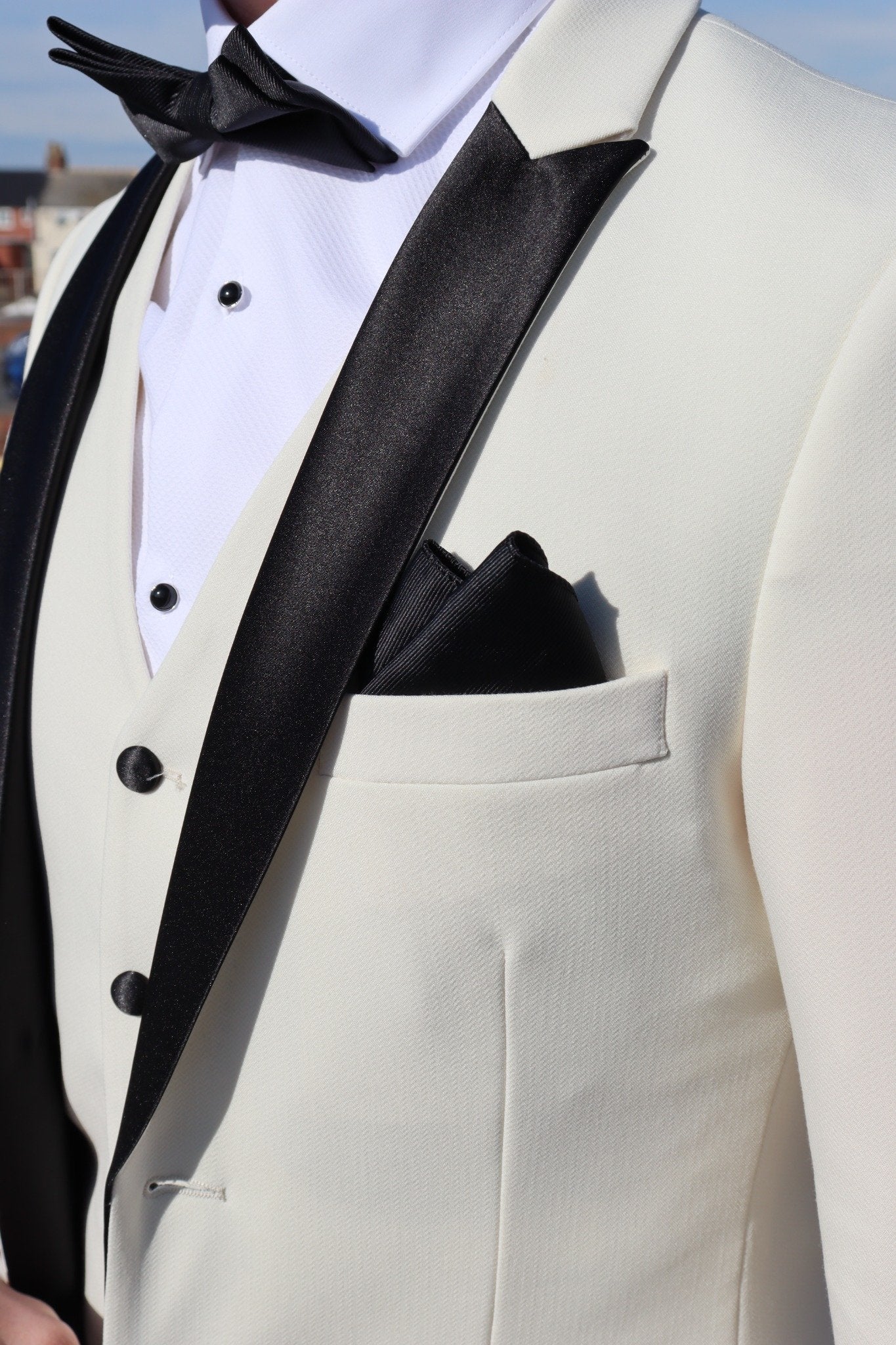 Close-up of the SUITBAE Diablo Ivory Three-Piece Tuxedo showing the black satin peak lapel, matching black buttons and pocket square — premium ivory tuxedo perfect for weddings, proms and black-tie occasions, available in plus sizes.
