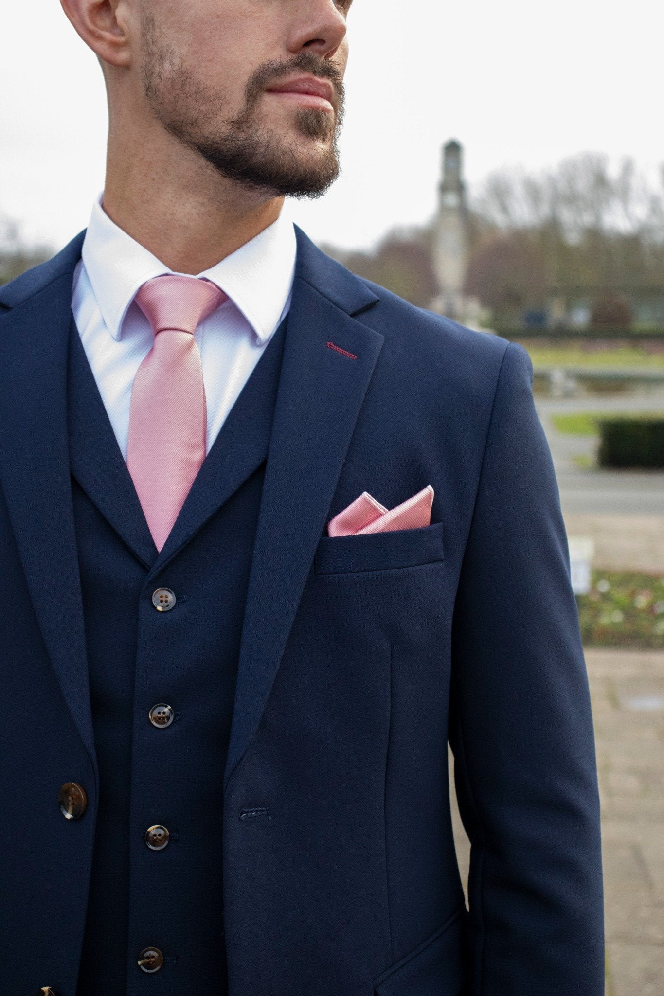 A closeup picture of a man wearing the Lawrence Navy suit showing the jacket, waistcoat and white shirt. Finished off with a mauve tie and pocket square.