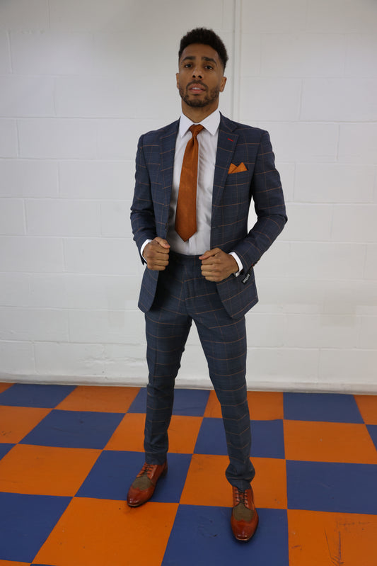 Model wearing the SUITBAE Thomas Check Two Piece Suit in navy with a bold textured pattern, styled with a burnt orange tie, pocket square and tan brogues — perfect for weddings, races and statement formalwear looks.